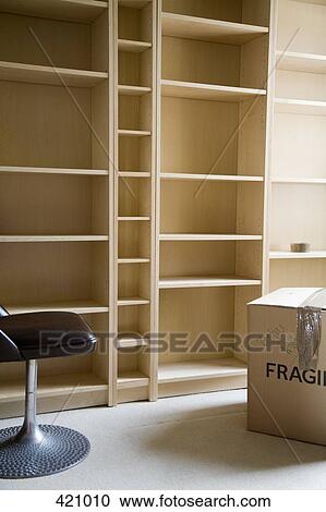 A chair and a cardboard box in front of empty bookshelves View Large Photo Image Stock Image - A chair and a cardboard box in front of empty bookshelves. Fotosearch