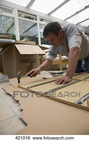 A man using a hammer to assemble furniture in a conservatory View Large Photo Image Stock Photograph - A man using a hammer to assemble furniture in a conservatory. Fotosearch