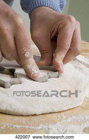 Stock Photo - A man making heart shaped cookies. Fotosearch