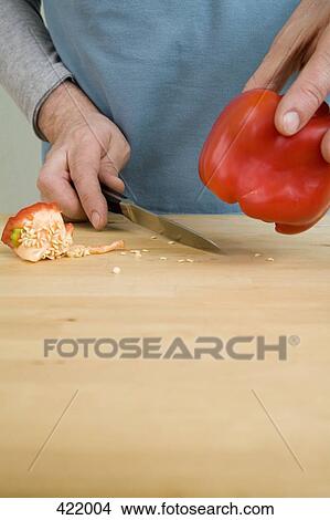 Picture - A man removing seeds from a red bell pepper. Fotosearch