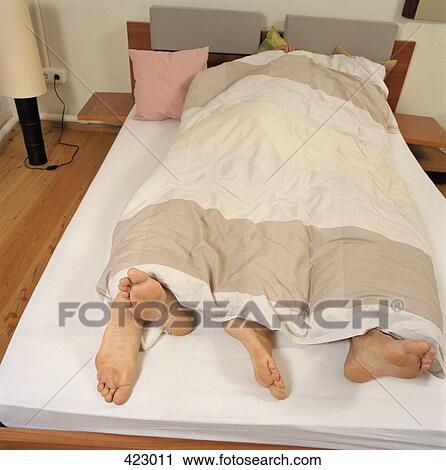 Young couple lying in a bed with their feet poking out the end View Large Photo Image Stock Image - Young couple lying in a bed with their feet poking out the end. Fotosearch