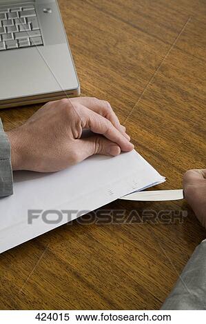 Stock Photography - Businessman opening an envelope with a letter opener. Fotosearch