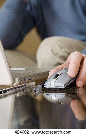 Man using a laptop with a mouse on a glass coffee table View Large Photo Image Stock Image - Man using a laptop with a mouse on a glass coffee table. Fotosearch
