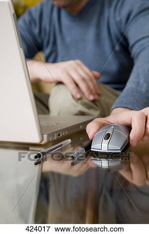 Man using a laptop with a mouse on a glass table View Large Photo Image Stock Photo - Man using a laptop with a mouse on a glass table. Fotosearch