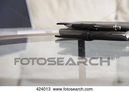 Personal organizer on a glass coffee table in front of a laptop on a sofa View Large Photo Image Stock Image - Personal organizer on a glass coffee table in front of a laptop on a sofa. Fotosearch