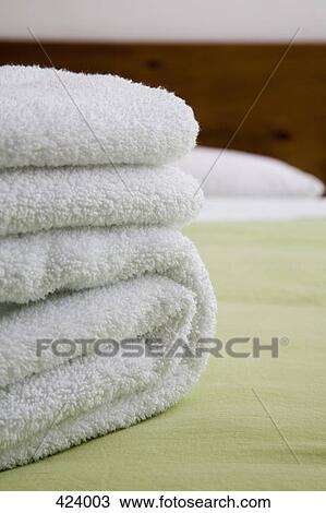Stack of towels on the edge on a bed in a hotel room View Large Photo Image Stock Image - Stack of towels on the edge on a bed in a hotel room. Fotosearch
