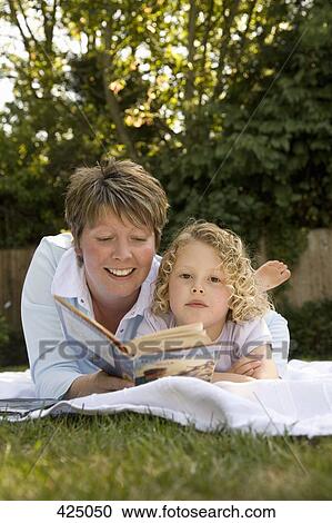 A woman and a young girl reading a book in the backyard View Large Photo Image Stock Image - A woman and a young girl reading a book in the backyard. Fotosearch