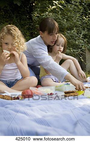 Stock Image - A woman and two girls having a picnic. Fotosearch
