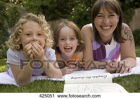 A woman and two girls laughing whilst lying down in a backyard View Large Photo Image Stock Image - A woman and two girls laughing whilst lying down in a backyard. Fotosearch