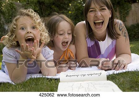 A woman and two girls laughing whilst lying down in a backyard View Large Photo Image Stock Image - A woman and two girls laughing whilst lying down in a backyard. Fotosearch
