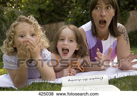 A woman and two girls screaming whilst lying down in a backyard View Large Photo Image Stock Photo - A woman and two girls screaming whilst lying down in a backyard. Fotosearch