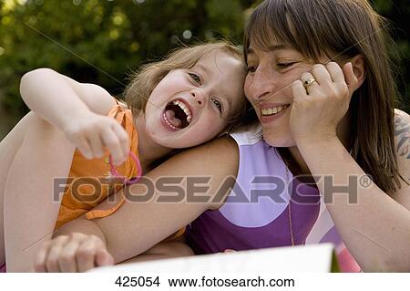Mother and daughter lying down and laughing together in a backyard View Large Photo Image Picture - Mother and daughter lying down and laughing together in a backyard. Fotosearch