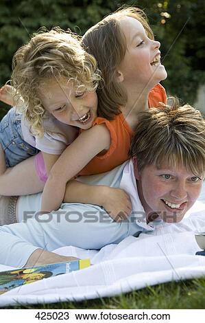 Two girls piled on top of a woman lying on a picnic blanket View Large Photo Image Stock Image - Two girls piled on top of a woman lying on a picnic blanket. Fotosearch