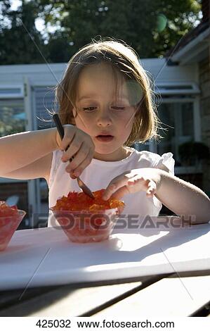 Young girl eating jello at a table in a backyard View Large Photo Image Stock Image - Young girl eating jello at a table in a backyard. Fotosearch
