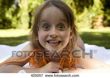 Young girl lying down on a blanket in a backyard View Large Photo Image Stock Photo - Young girl lying down on a blanket in a backyard. Fotosearch