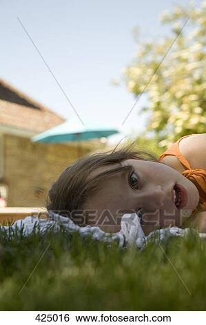 Young girl lying down on a blanket in a backyard View Large Photo Image Stock Photograph - Young girl lying down on a blanket in a backyard. Fotosearch
