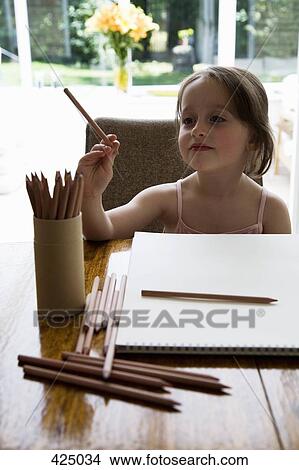 Young girl sitting at a table with a sketch pad and colored pencils View Large Photo Image Picture - Young girl sitting at a table with a sketch pad and colored pencils. Fotosearch