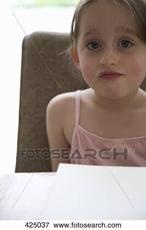 Young girl sitting at a table with a sketch pad View Large Photo Image Stock Photo - Young girl sitting at a table with a sketch pad. Fotosearch