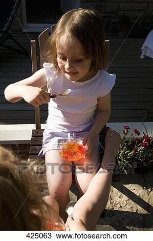 Young girl sitting in a backyard eating jello View Large Photo Image Stock Image - Young girl sitting in a backyard eating jello. Fotosearch