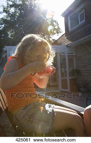 Young girl sitting on a chair in a backyard eating jello View Large Photo Image Stock Image - Young girl sitting on a chair in a backyard eating jello. Fotosearch