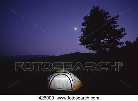Stock Image - Illuminated tent in a field at night. Fotosearch