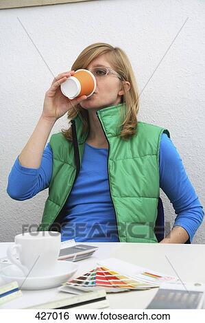 Woman drinking coffee at desk View Large Photo Image Stock Photograph - Woman drinking coffee at desk. Fotosearch