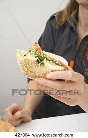Picture - Woman eating bagel. Fotosearch