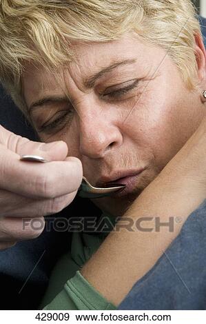 Stock Photo - A woman taking medicine from a spoon. Fotosearch