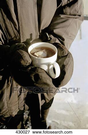 Stock Photo - Man wearing ski wear and holding a cup of tea. Fotosearch
