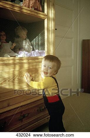 Boy standing next to dolls on a shelf View Large Photo Image Picture - Boy standing next to dolls on a shelf. Fotosearch