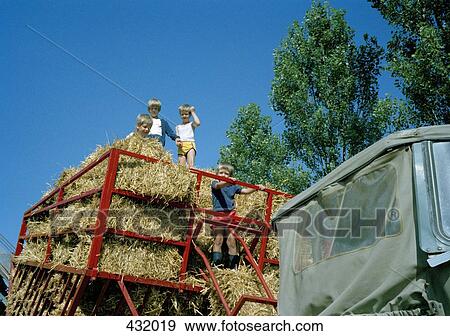 Children standing in hay bales on tractor View Large Photo Image Stock Photo - Children standing in hay bales on tractor. Fotosearch