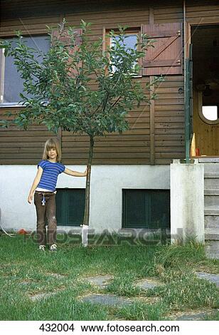 Picture - Girl standing next to a tree. Fotosearch