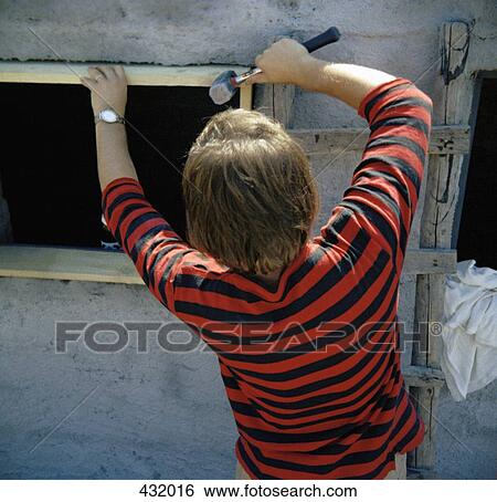 Stock Photograph - Rear view of man using hammer. Fotosearch