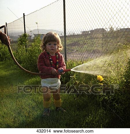 Picture - Young girl watering the garden witha hosepipe. Fotosearch