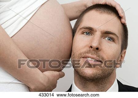 Man putting his head up to a pregnant woman's stomach View Large Photo Image Picture - Man putting his head up to a pregnant woman's stomach. Fotosearch