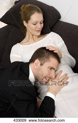 Man putting his head up to a pregnant woman's stomach View Large Photo Image Stock Photo - Man putting his head up to a pregnant woman's stomach. Fotosearch