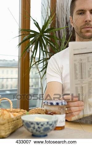 Stock Photo - Man reading a newspaper over breakfast. Fotosearch