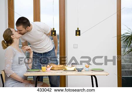 Pregnant couple kissing over breakfast View Large Photo Image Stock Image - Pregnant couple kissing over breakfast. Fotosearch