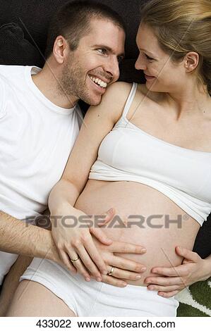 Stock Image - Pregnant couple lying down together. Fotosearch
