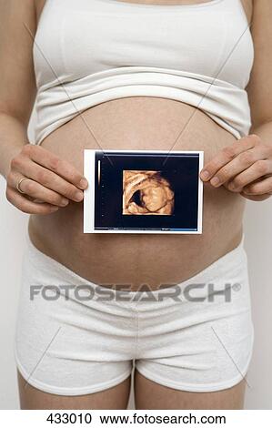 Stock Image - Pregnant woman holding an ultrasound image. Fotosearch