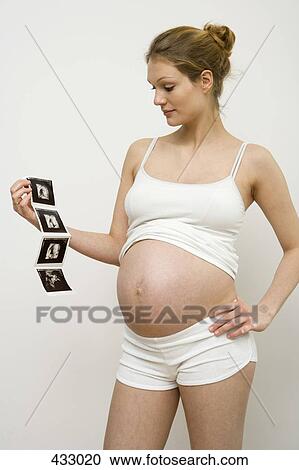 Stock Image - Pregnant woman holding ultrasound images. Fotosearch