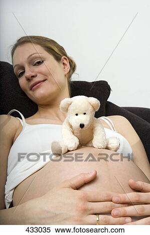 Pregnant woman sitting down with a teddy bear on her stomach View Large Photo Image Stock Photography - Pregnant woman sitting down with a teddy bear on her stomach. Fotosearch