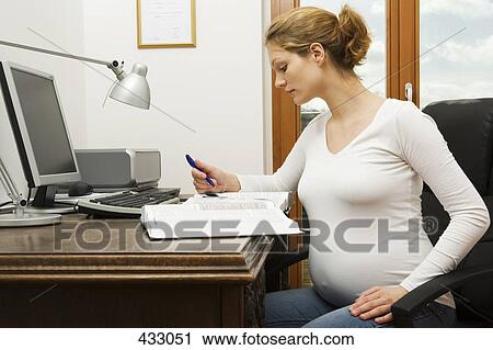 Stock Image - Pregnant woman working from home. Fotosearch