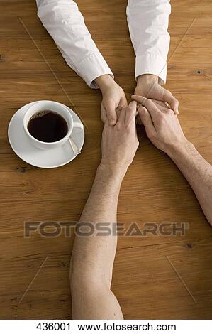 A couple holding hands across a table Standartiniai ...