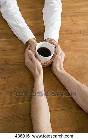 Stock Photograph - A couple holding hands across a table. Fotosearch