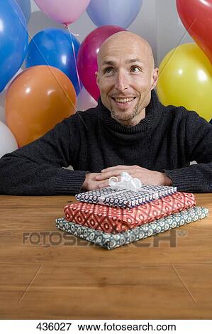 A man sitting at a table with balloons and gifts View Large Photo Image Stock Photo - A man sitting at a table with balloons and gifts. Fotosearch