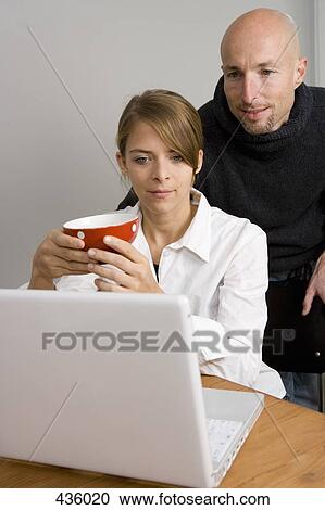 Stock Image - Couple looking at laptop together. Fotosearch