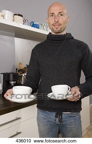 Man holding cups in the kitchen View Large Photo Image Stock Image - Man holding cups in the kitchen. Fotosearch