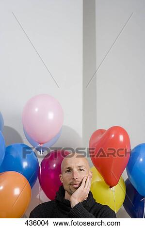 Picture - Man sitting amongst balloons. Fotosearch