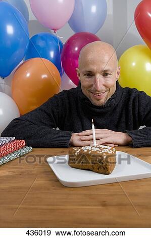Man sitting at table with birthday cake and balloons View Large Photo Image Stock Photo - Man sitting at table with birthday cake and balloons. Fotosearch